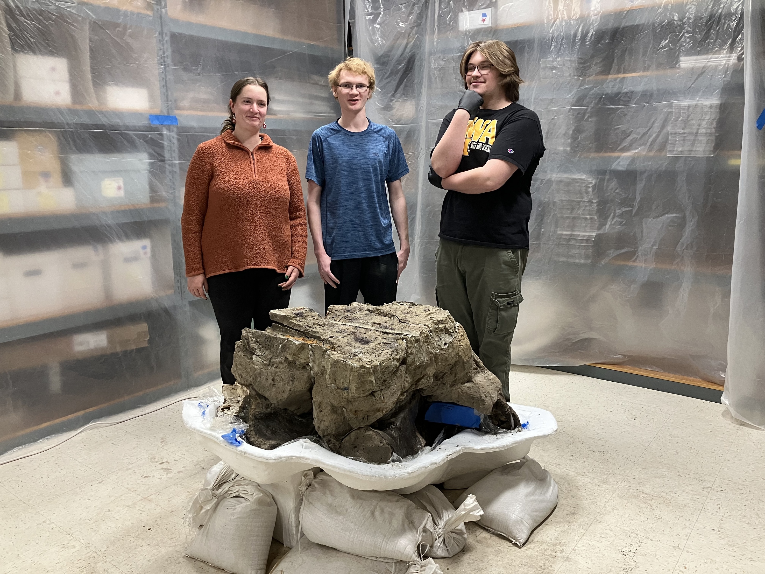 Three students looking at a mastodon skull 